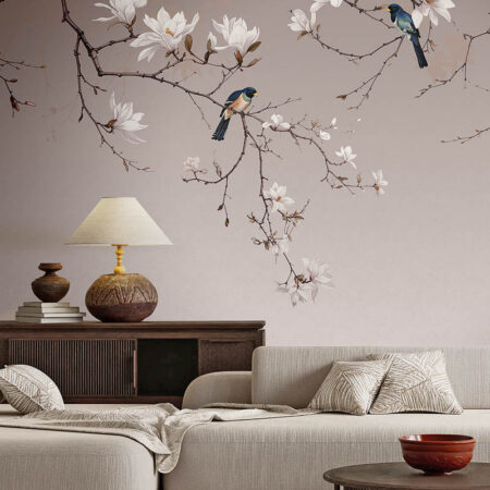 Mudita III botanical bird wallpaper installed above a cream sectional sofa in a warm contemporary living room.