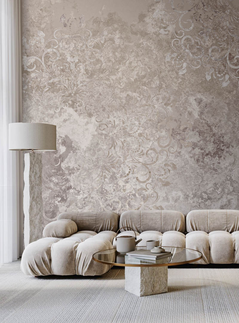 Oriema contemporary wallpaper by Artedimuro, showcasing delicate ornate patterns on a natural stone-textured background in a modern living room setting with plush seating and minimalist decor.